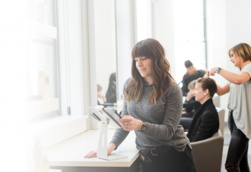 Hair stylist looking at tablet in salon