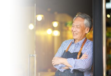 Happy owner with arms crossed at restaurant