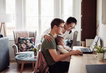 Shot of a couple looking at something on a laptop while sitting with their baby
