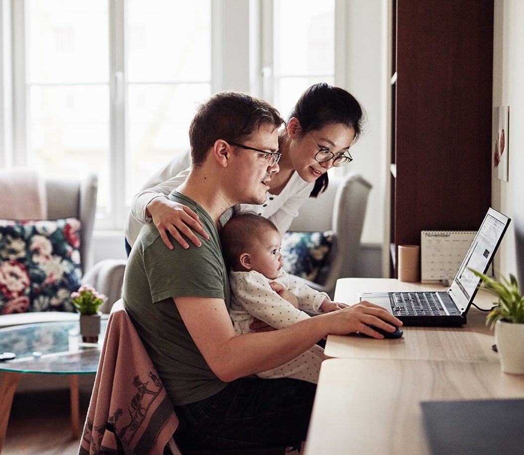 Shot of a couple looking at something on a laptop while sitting with their baby
