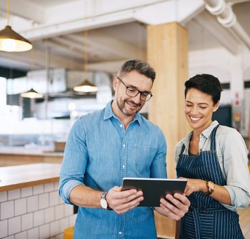 Shot of a man and woman using a digital tablet together in their coffee shop