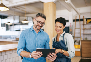 Shot of a man and woman using a digital tablet together in their coffee shop