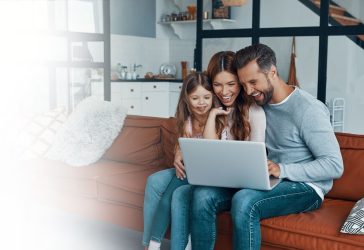 family sitting on couch looking at laptop