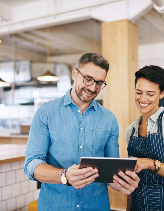 man and woman looking at ipad in a restaurant
