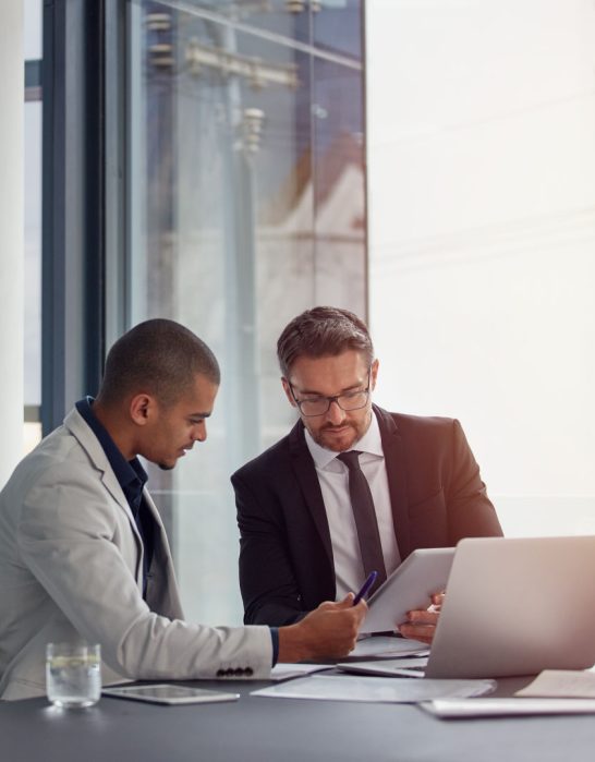 two men in conference room reviewing things on an iPad