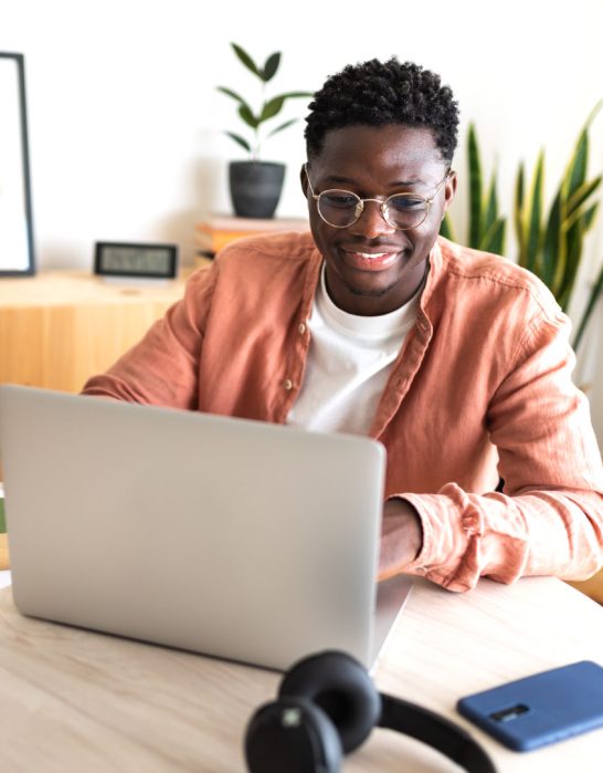 black man sitting at table with laptop