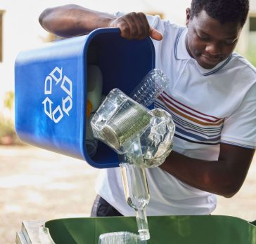Man pouring recycling into a bigger bin.