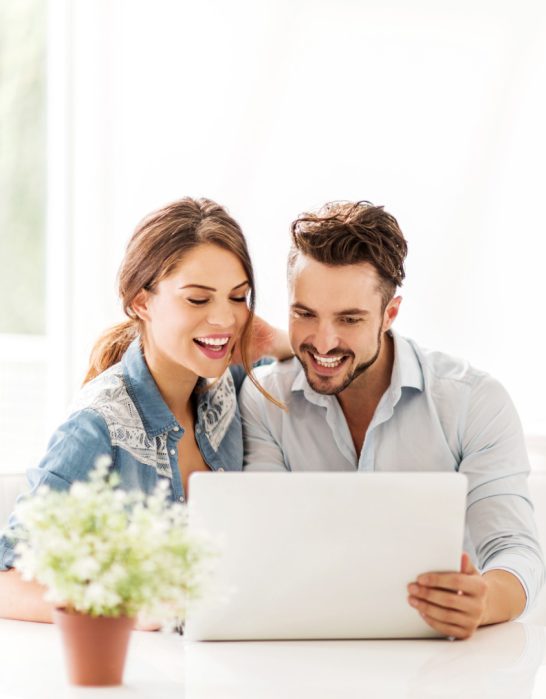 happy couple looking at laptop