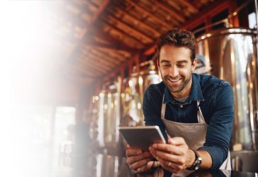 Smiling man working at brewery looking at iPad