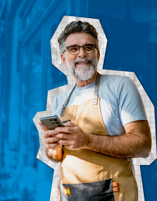 Small business owner smiling while holding a phone outside his business.